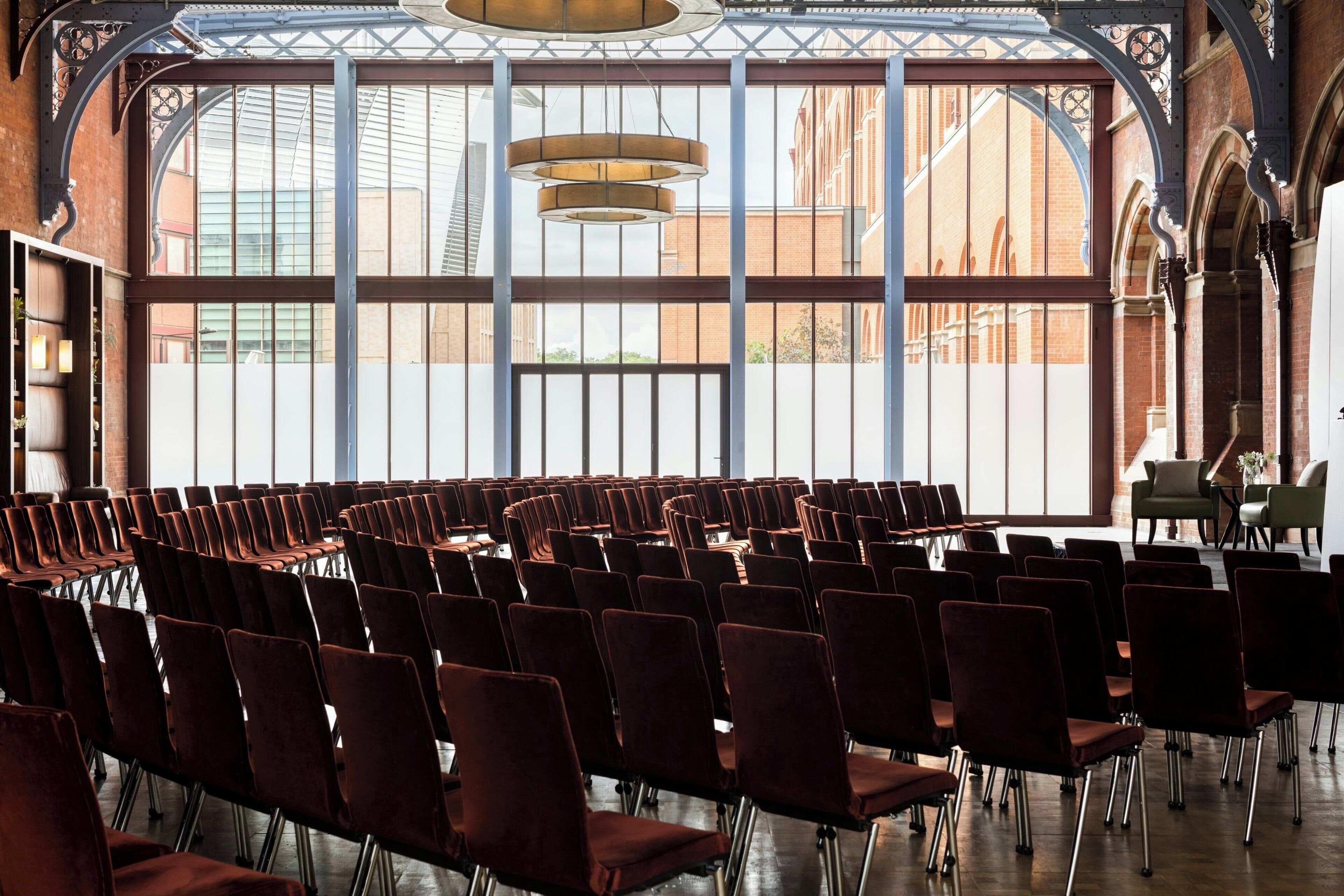 Ein Konferenzraum mit Reihen von Stühlen, großen Fenstern und einer modernen Kronleuchter.