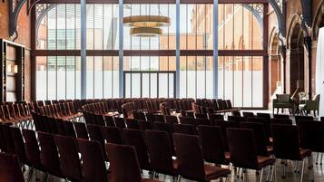 Ein Konferenzraum mit Reihen von Stühlen, großen Fenstern und einer modernen Kronleuchter.