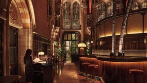 An interior with a bar area, wooden columns, and a woman at a desk. - St. Pancras London, Autograph Collection ® (London)