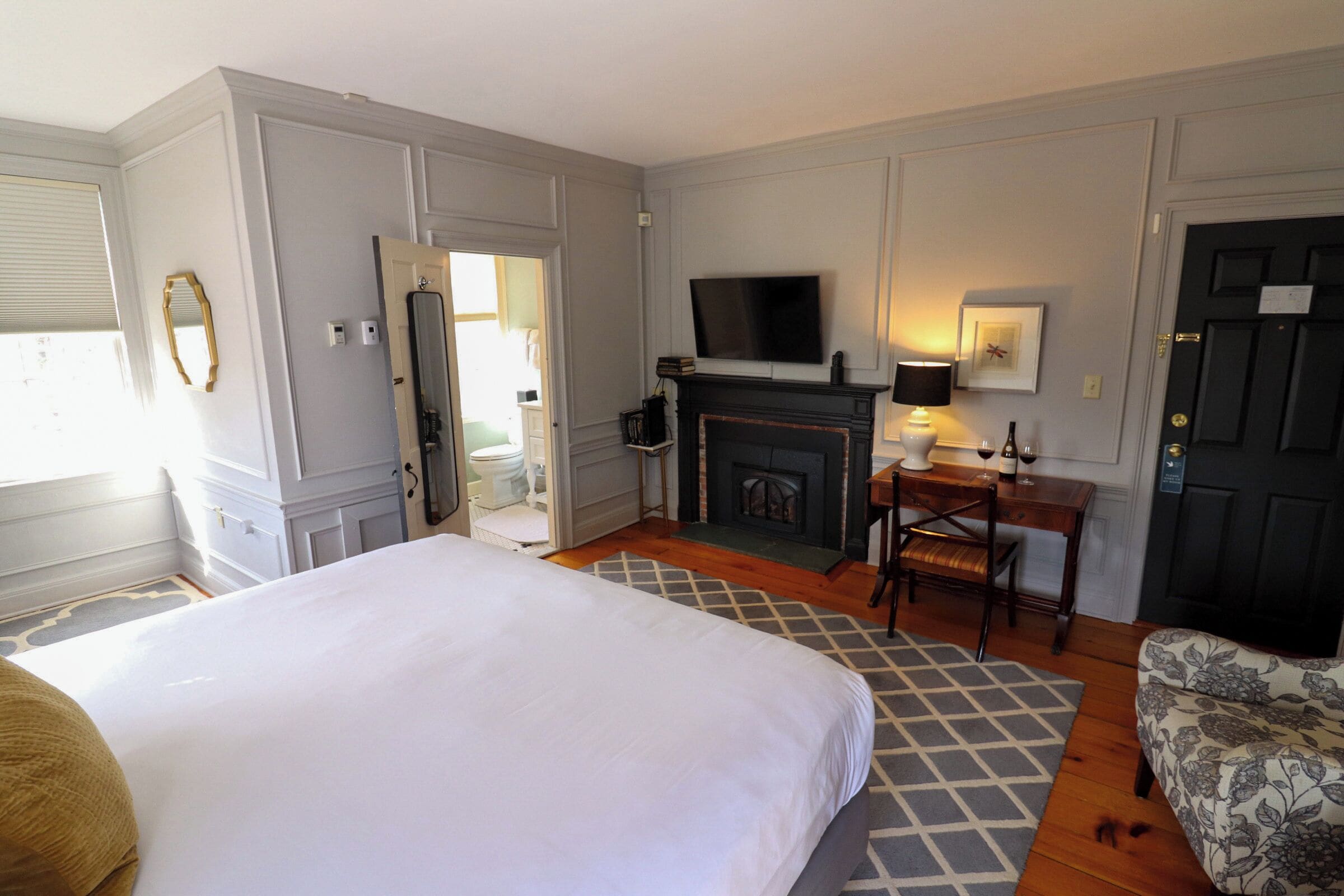 A hotel room with a large bed, a fireplace, a television, a desk, and a chair.