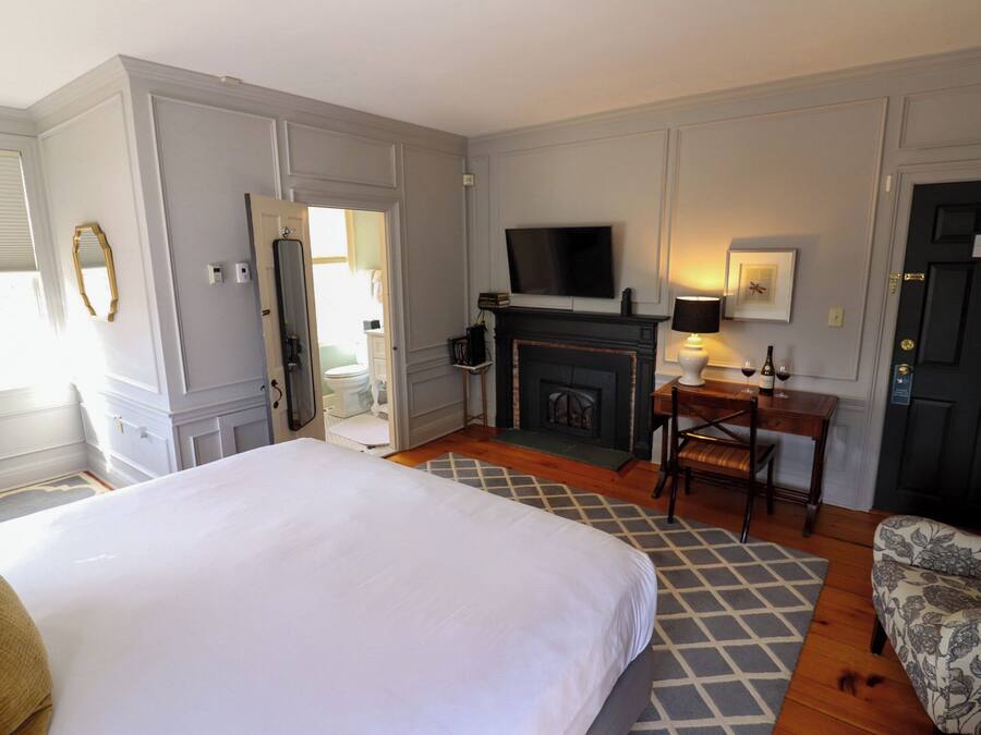 A hotel room with a large bed, a fireplace, a television, a desk, and a chair.