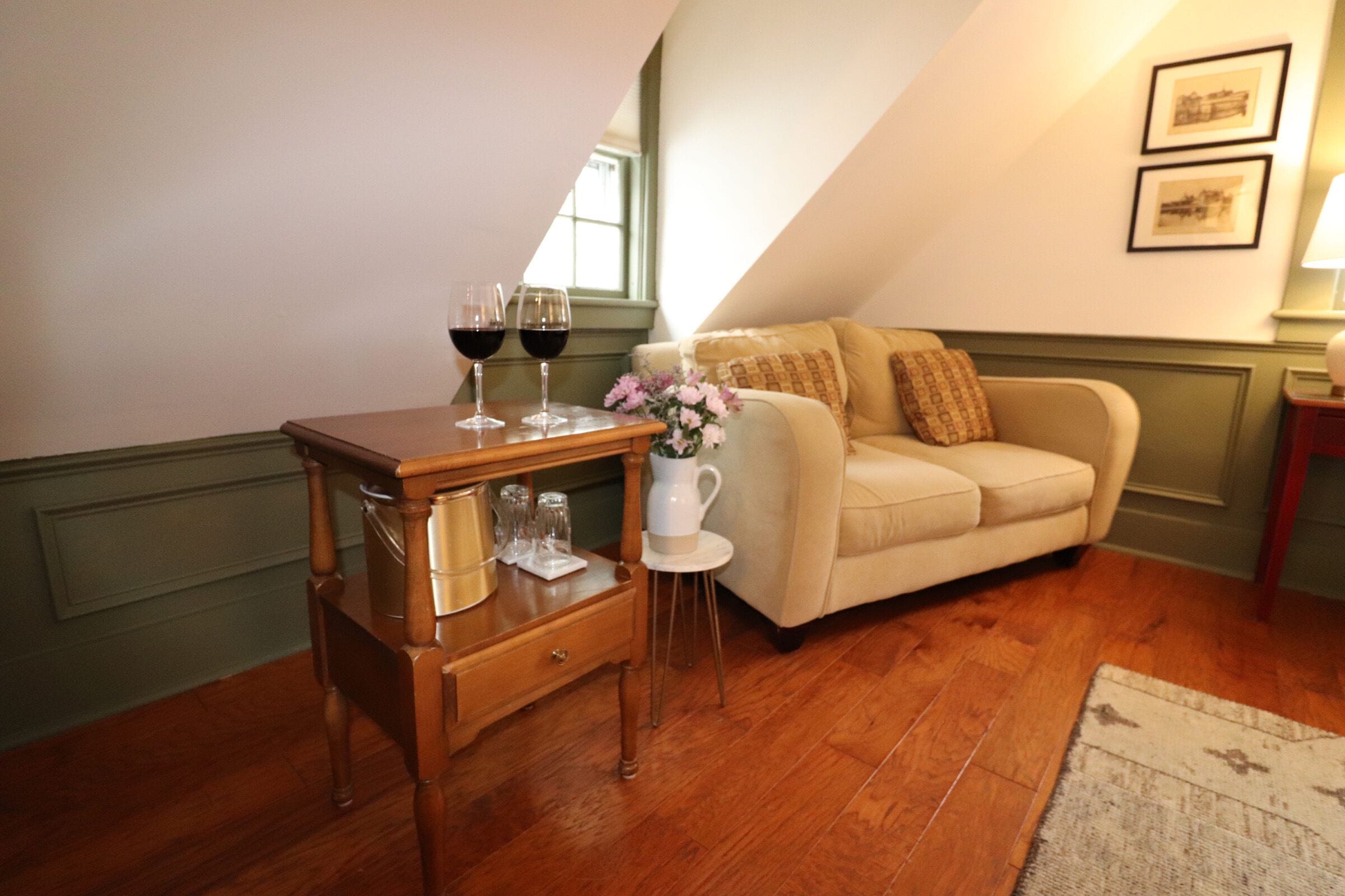 A cozy living room with a wooden coffee table, a beige sofa, and a small white side table with a vase of flowers.