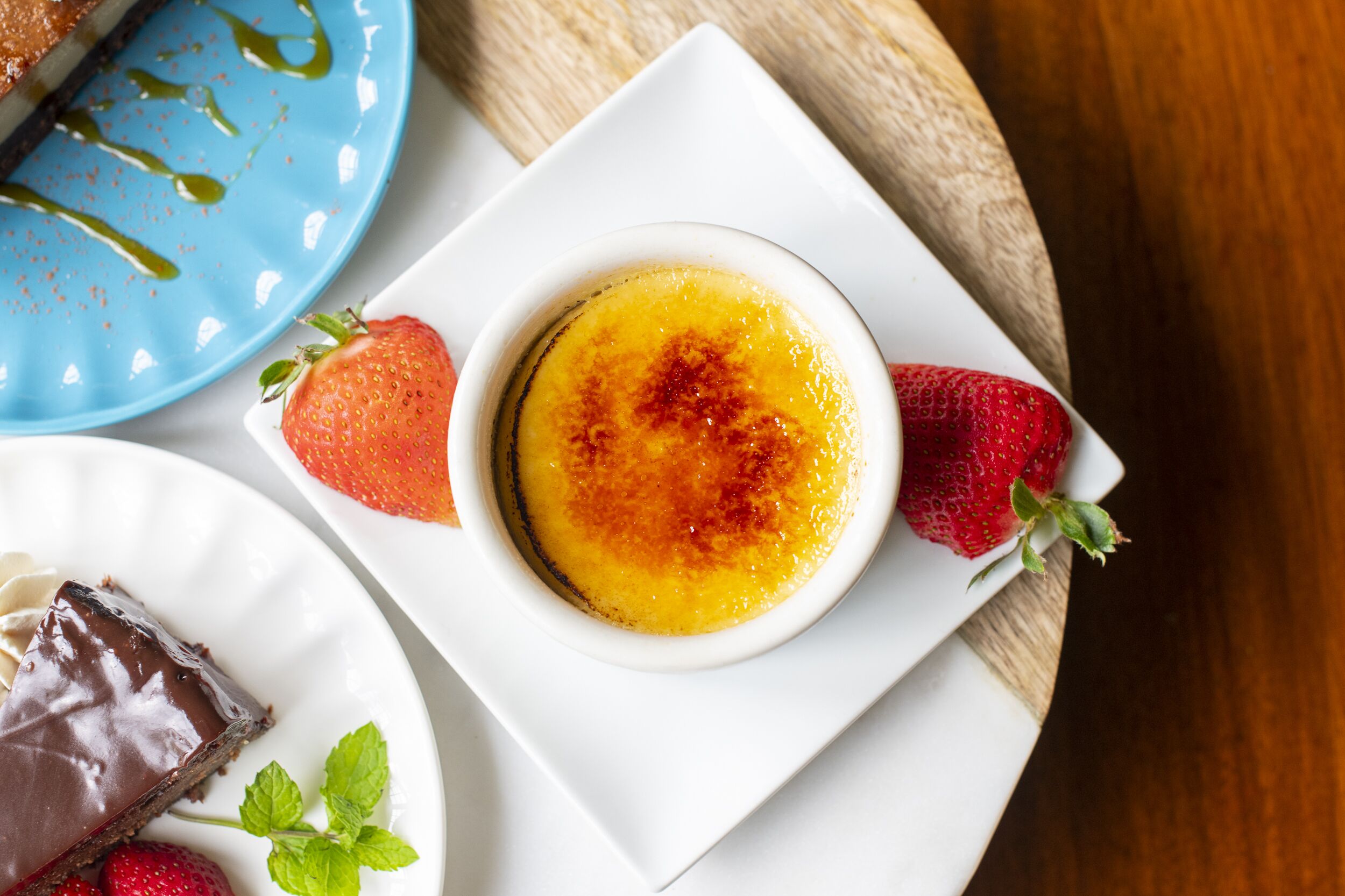Ein Dessertteller mit Crème brûlée, Erdbeeren und einem Schokoladentörtchen.