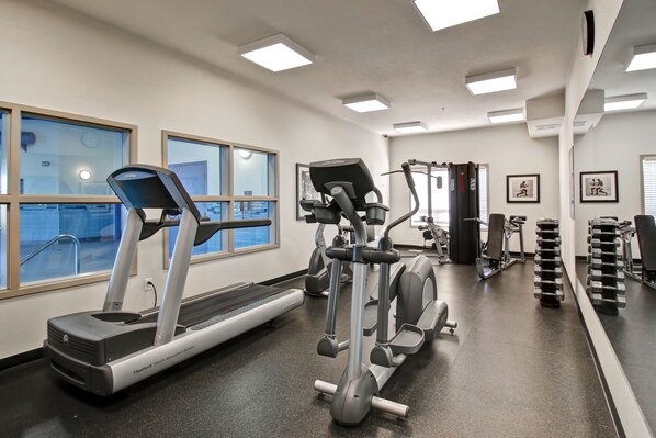A gym with treadmills, elliptical machines, and dumbbells.