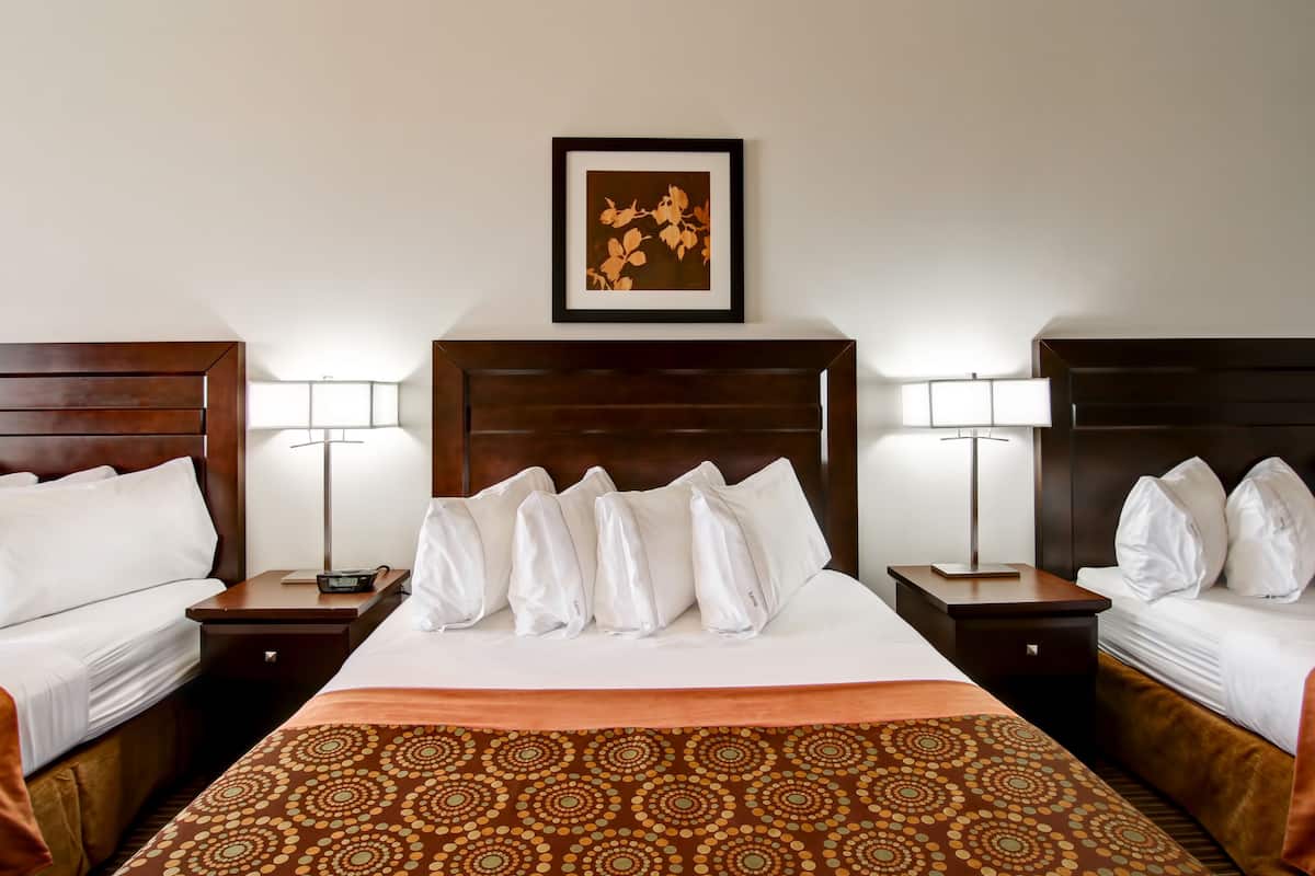 A hotel room with a large bed, two bedside tables, a nightstand, a framed picture on the wall, and a patterned bedspread.