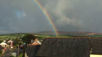 A rural landscape with a rainbow, houses, and a road.