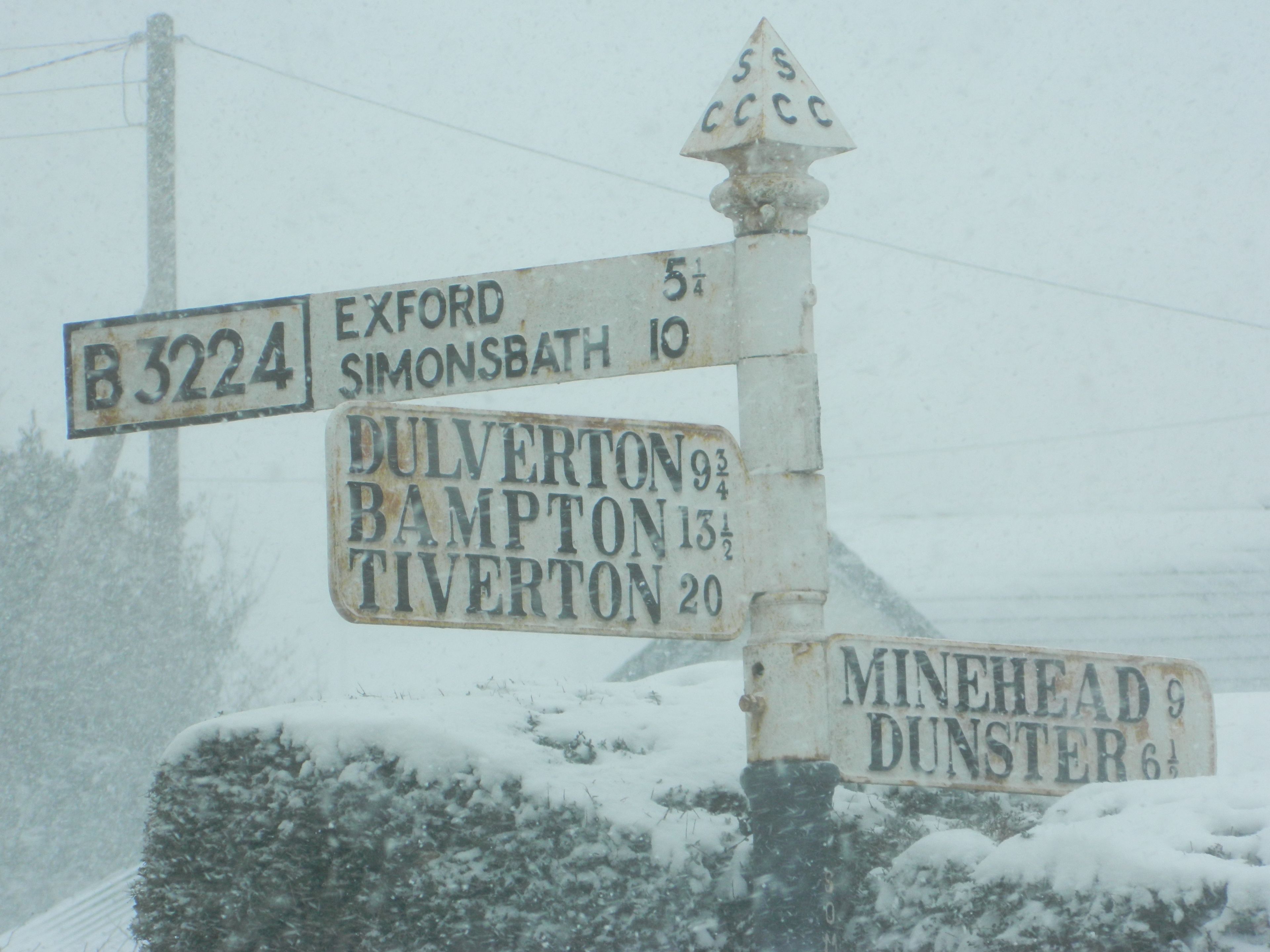 A weathered directional signpost with multiple route indications.