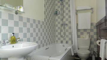 Un baño con pared de baldosas a cuadros, lavamanos, bañera, ducha e inodoro.