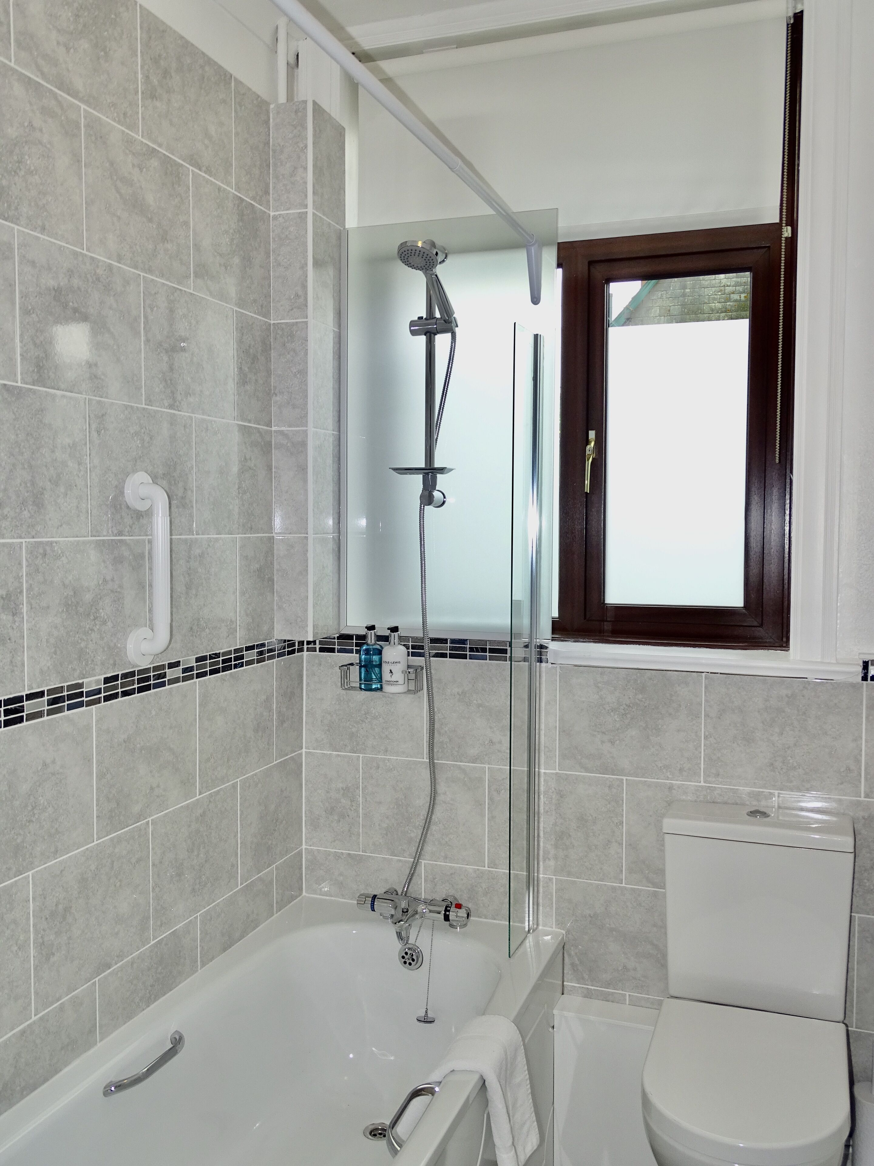 A modern bathroom with a bathtub, shower, and toilet.