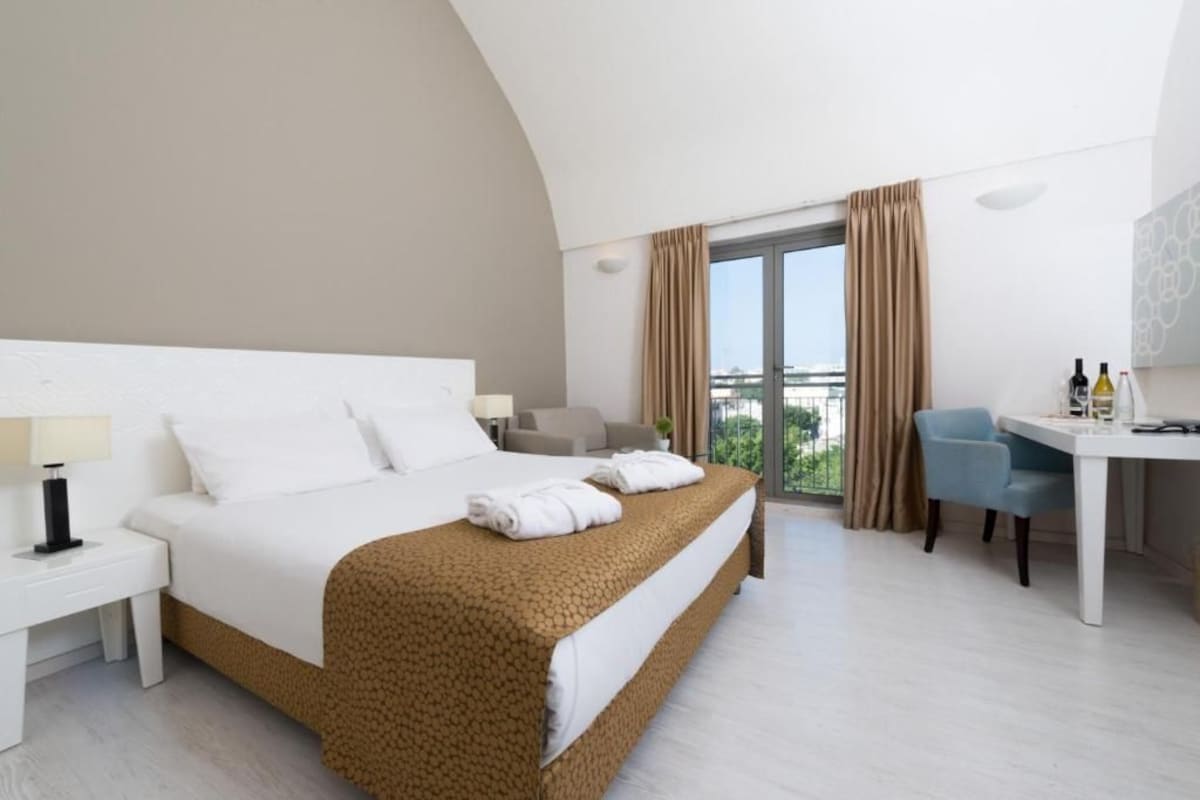 Habitació d'hotel amb un llit gran, un escriptori i vista a la ciutat.