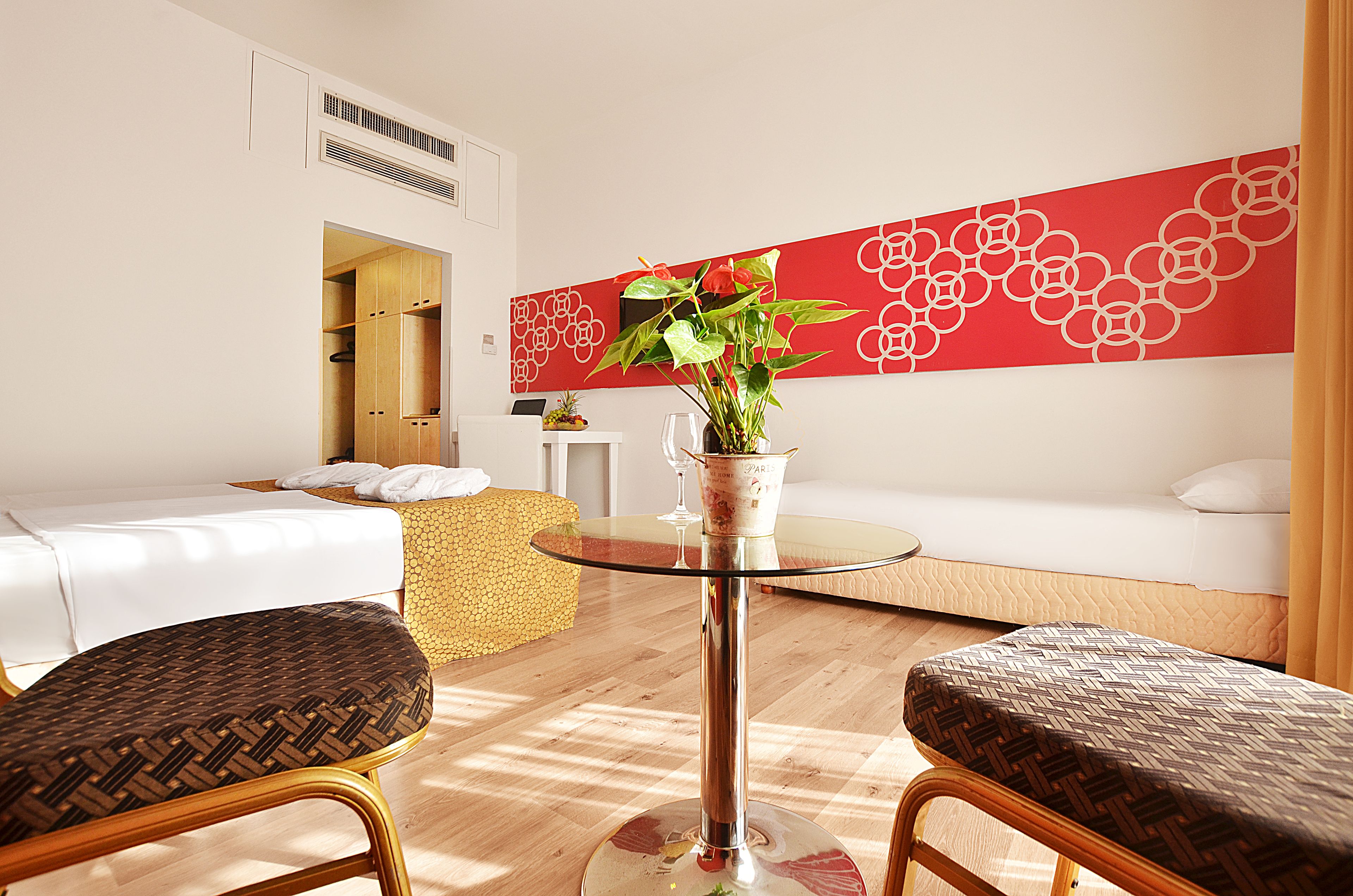 A modern hotel room with a sofa, two armchairs, a small table, and a decorative wall piece.