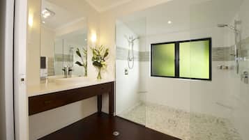 Une salle de bain moderne avec une douche à parois de verre, un grand miroir et un meuble-lavabo blanc.