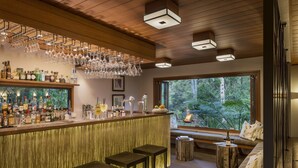 A bar area with a wooden ceiling, hanging wine glasses, and a view of greenery outside. - Spicers Tamarind Retreat (Maleny)