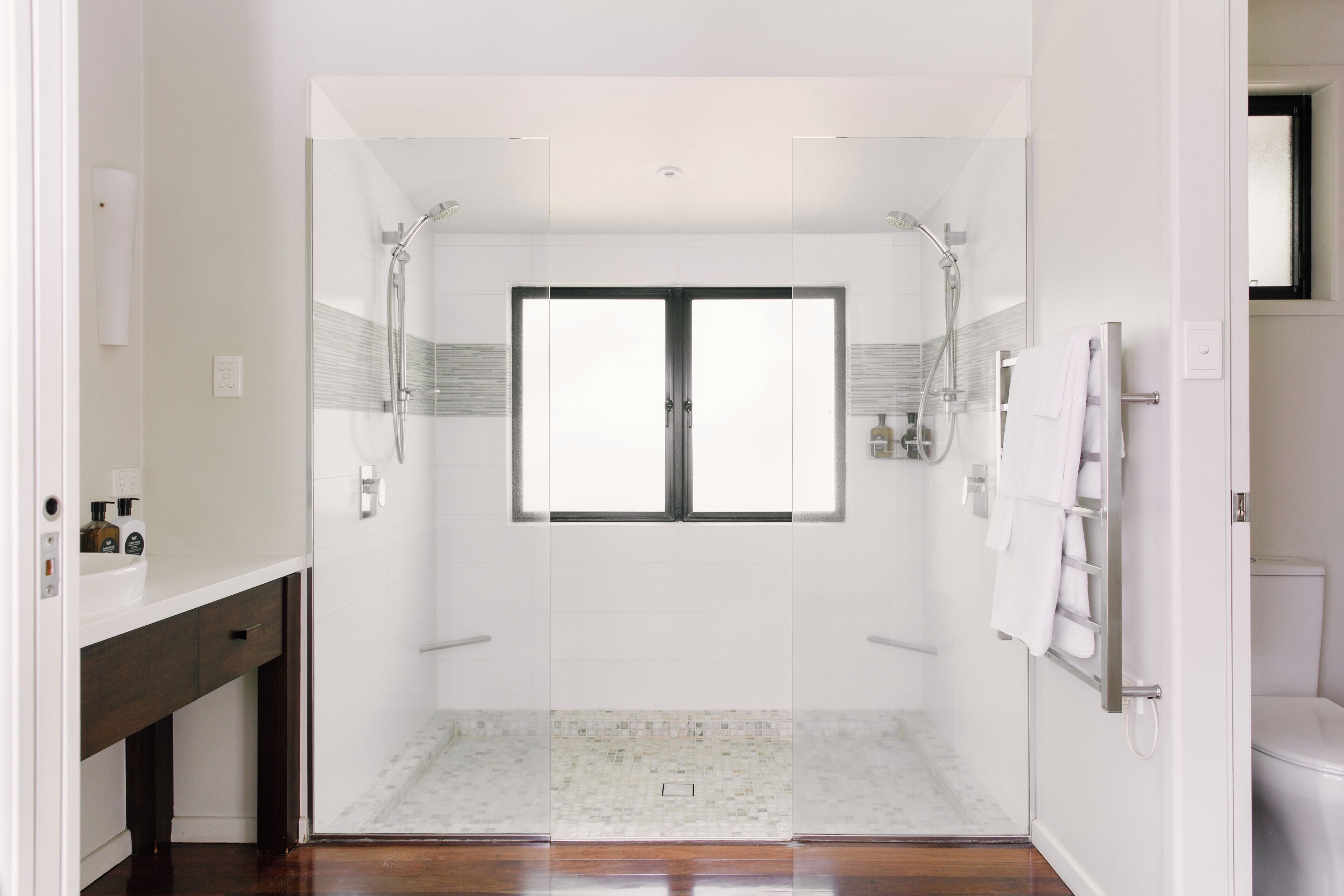 A modern bathroom with a glass-enclosed shower, a white sink, and a toilet.