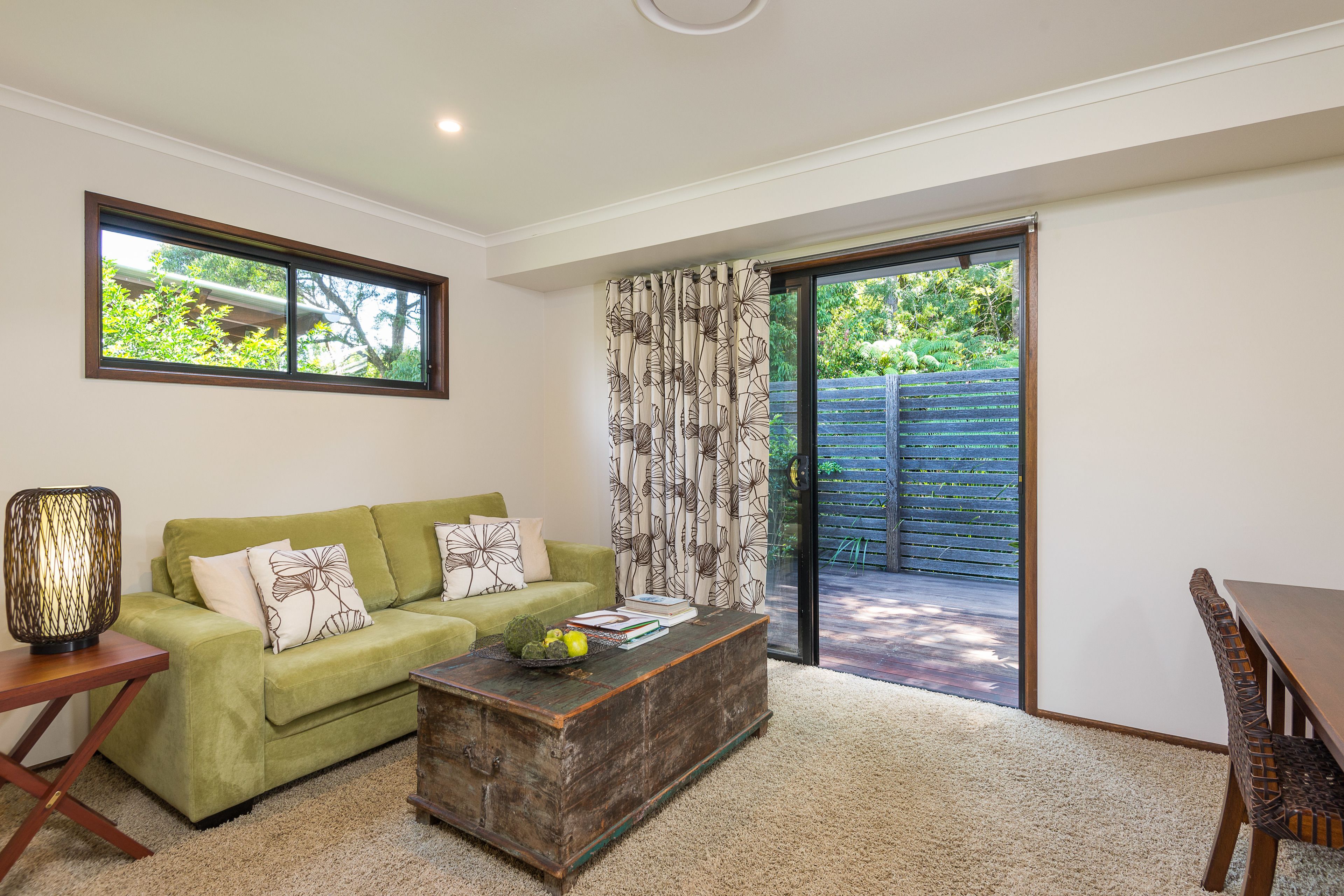 A living room with a green sofa, a wooden coffee table, and a dining table with chairs.