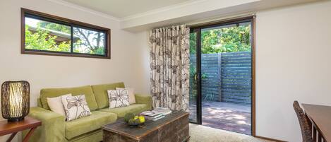 A living room with a green sofa, a wooden coffee table, and a dining table with chairs.