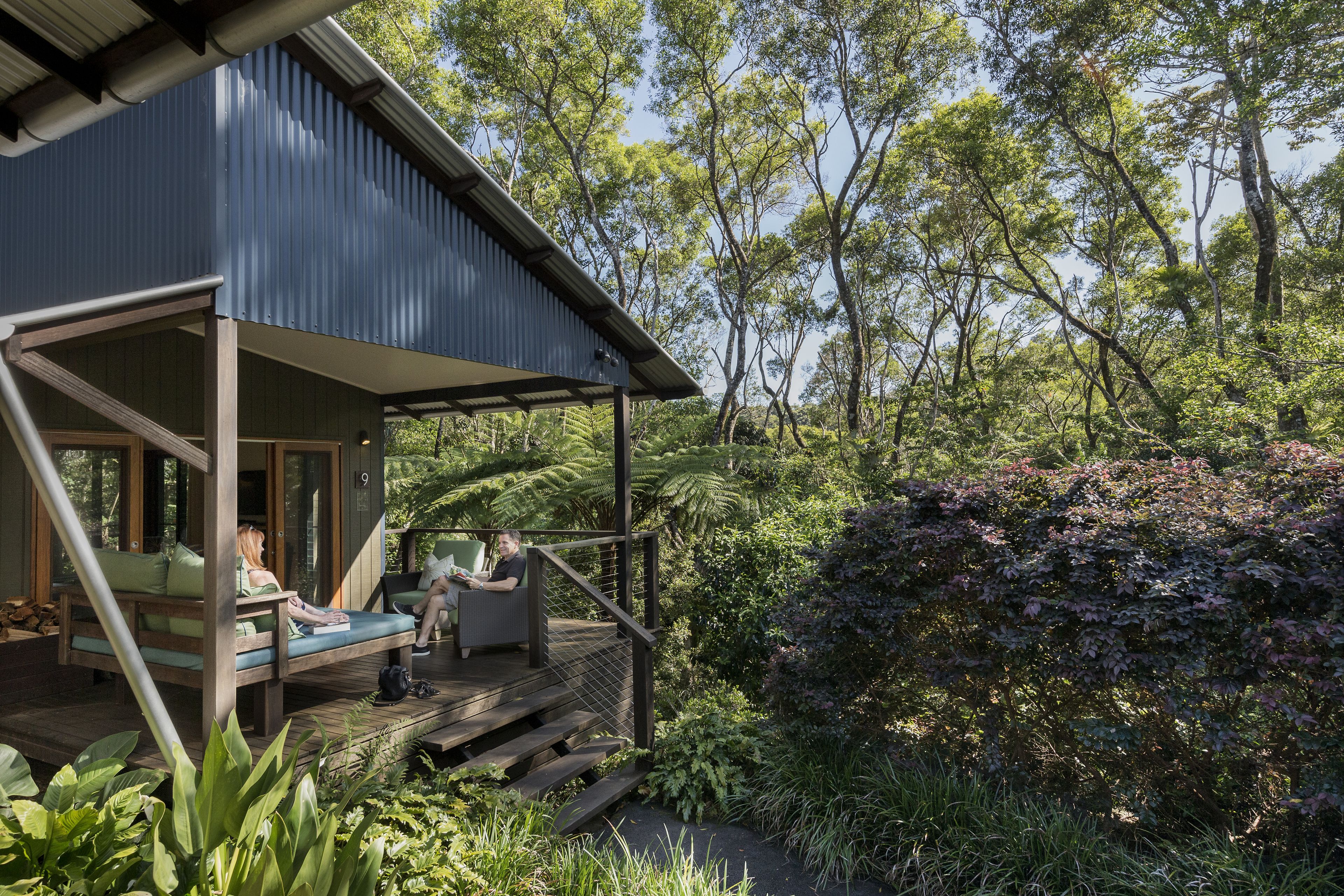 A wooden deck with seating, overlooking a lush garden and trees.