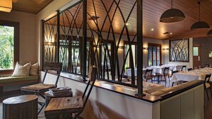 A restaurant with a wooden ceiling, black metal partitions, and tables set for dining. - Spicers Tamarind Retreat (Maleny)