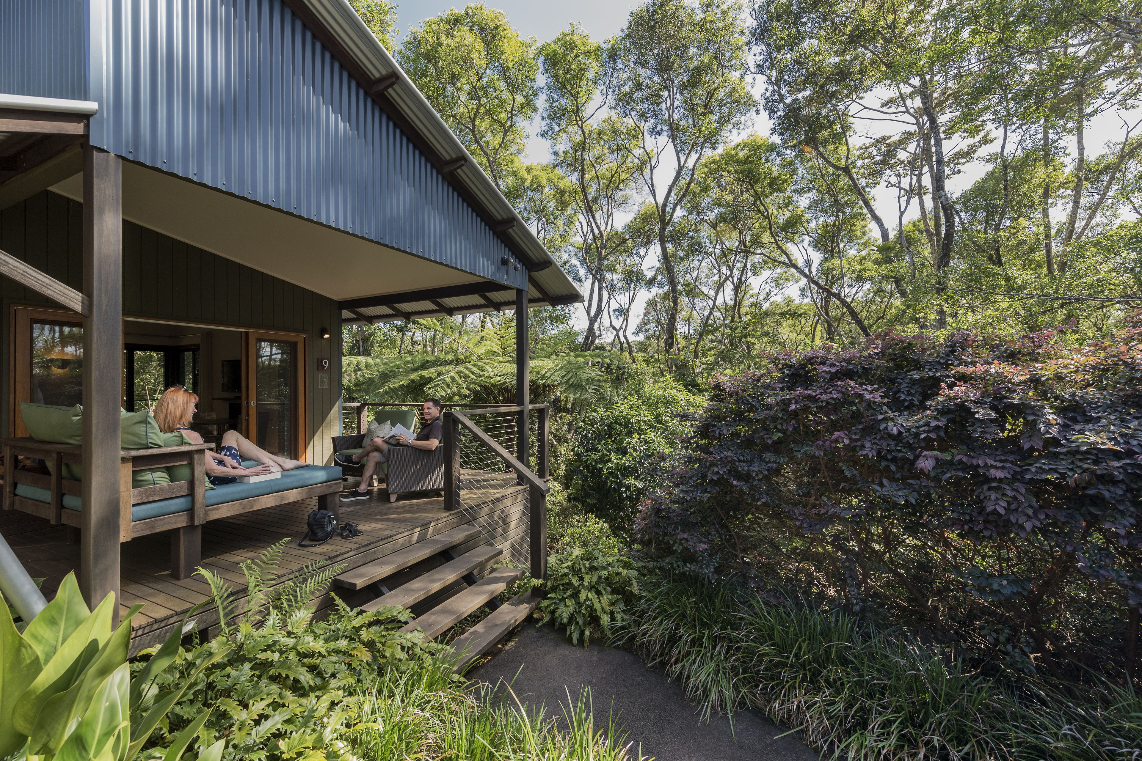 A wooden deck with seating, surrounded by lush greenery and trees.