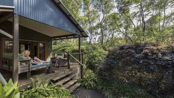 A wooden deck with seating, surrounded by lush greenery and trees.