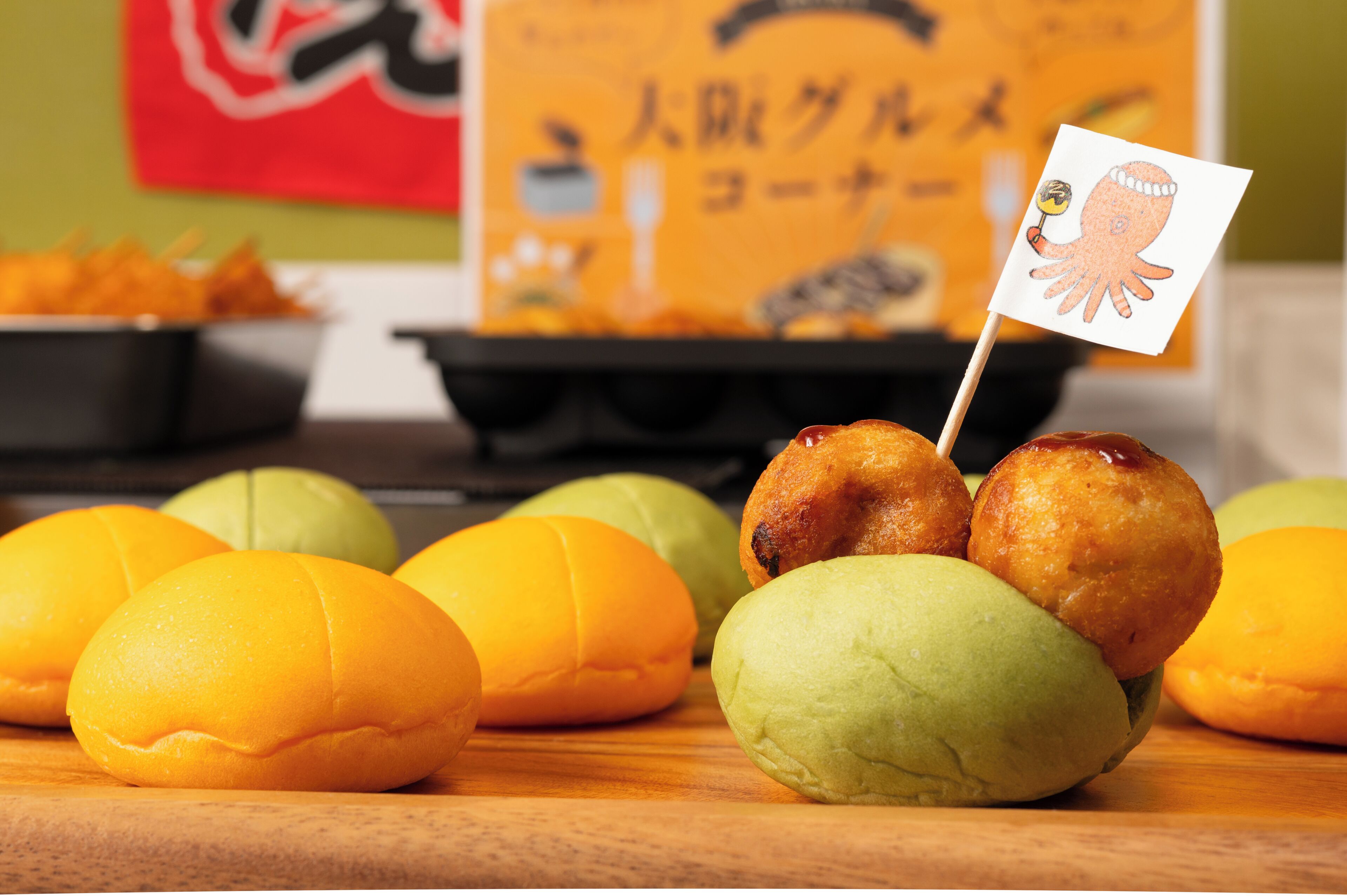 A wooden table with several round pastries and a small flag with an octopus design.