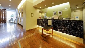 A hotel reception area with a marble counter, a wooden chair, and a clear view of the entrance. - Hotel the Lutheran (Osaka)