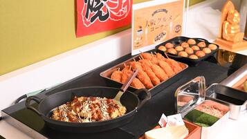 Una mesa de buffet con diversos platos, incluyendo frituras y una cazuela con un guiso cubierto de salsa.