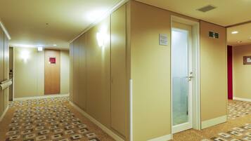 Un pasillo de hotel con alfombra estampada, paredes color beige y puertas que dan a habitaciones.