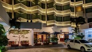 A hotel entrance with a modern design, featuring a curved ceiling, outdoor seating, and a white car parked nearby. - Hotel Plaza Cozumel (Cozumel)