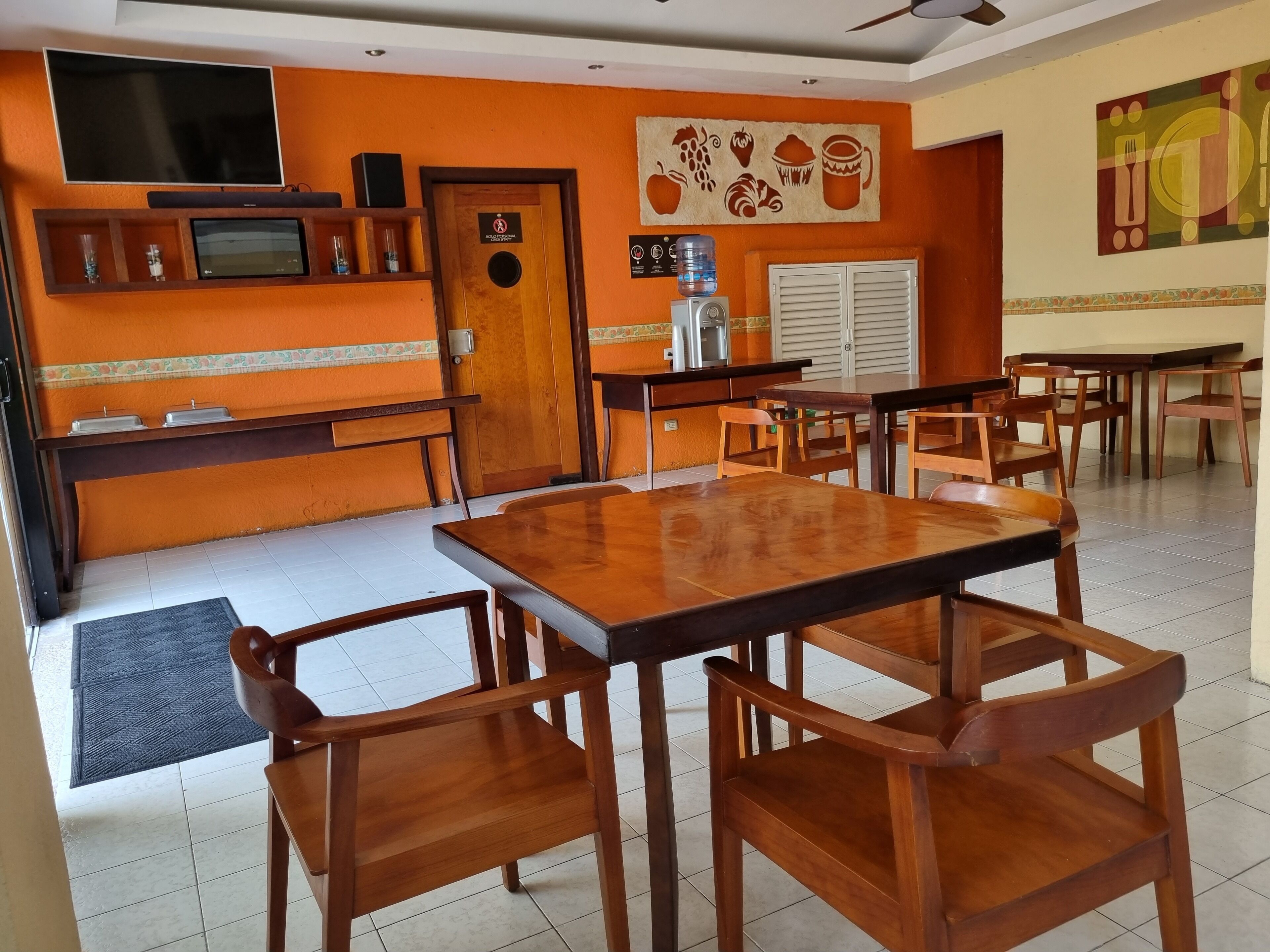 Un restaurante con mobiliario de madera, un televisor y un dispensador de agua.