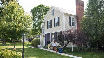 A two-story house with a brick chimney, a front porch, and a well-maintained lawn.