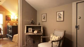A room with a vintage-style dresser, a striped armchair, and two framed pictures on the wall.