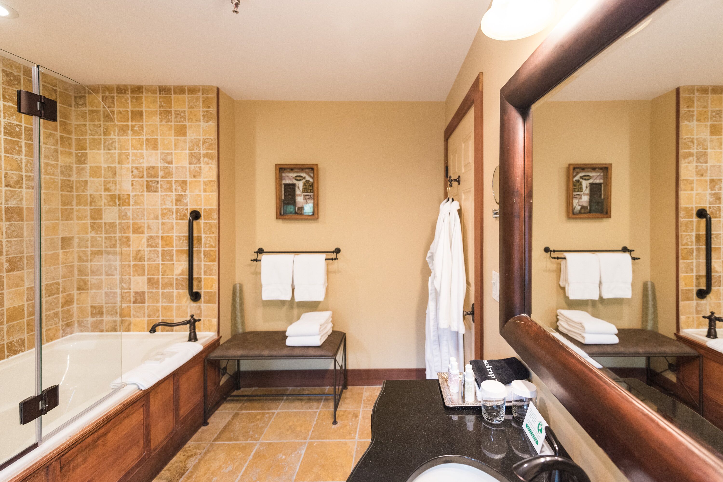 Une salle de bain avec une baignoire, un lavabo et un miroir. On y trouve des serviettes et des articles de toilette sur le comptoir.
