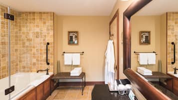 Ein Badezimmer mit Badewanne, Waschbecken und Spiegel. Handtücher und Toilettenartikel liegen auf der Ablagefläche.