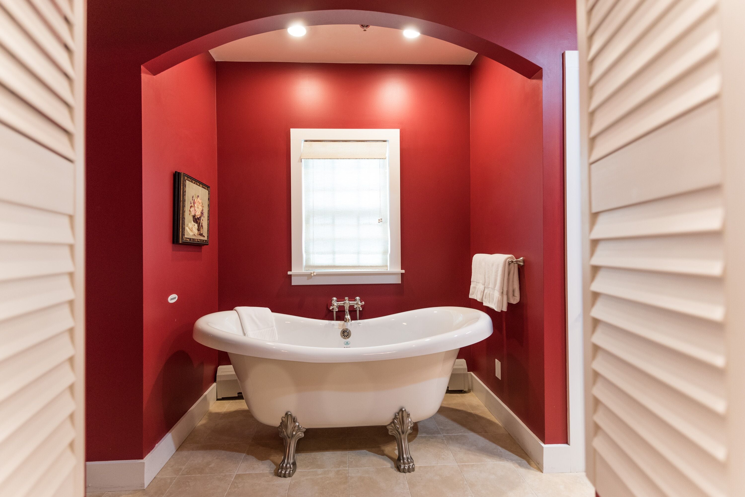 A bathroom with a freestanding bathtub, a window, and a towel rack.