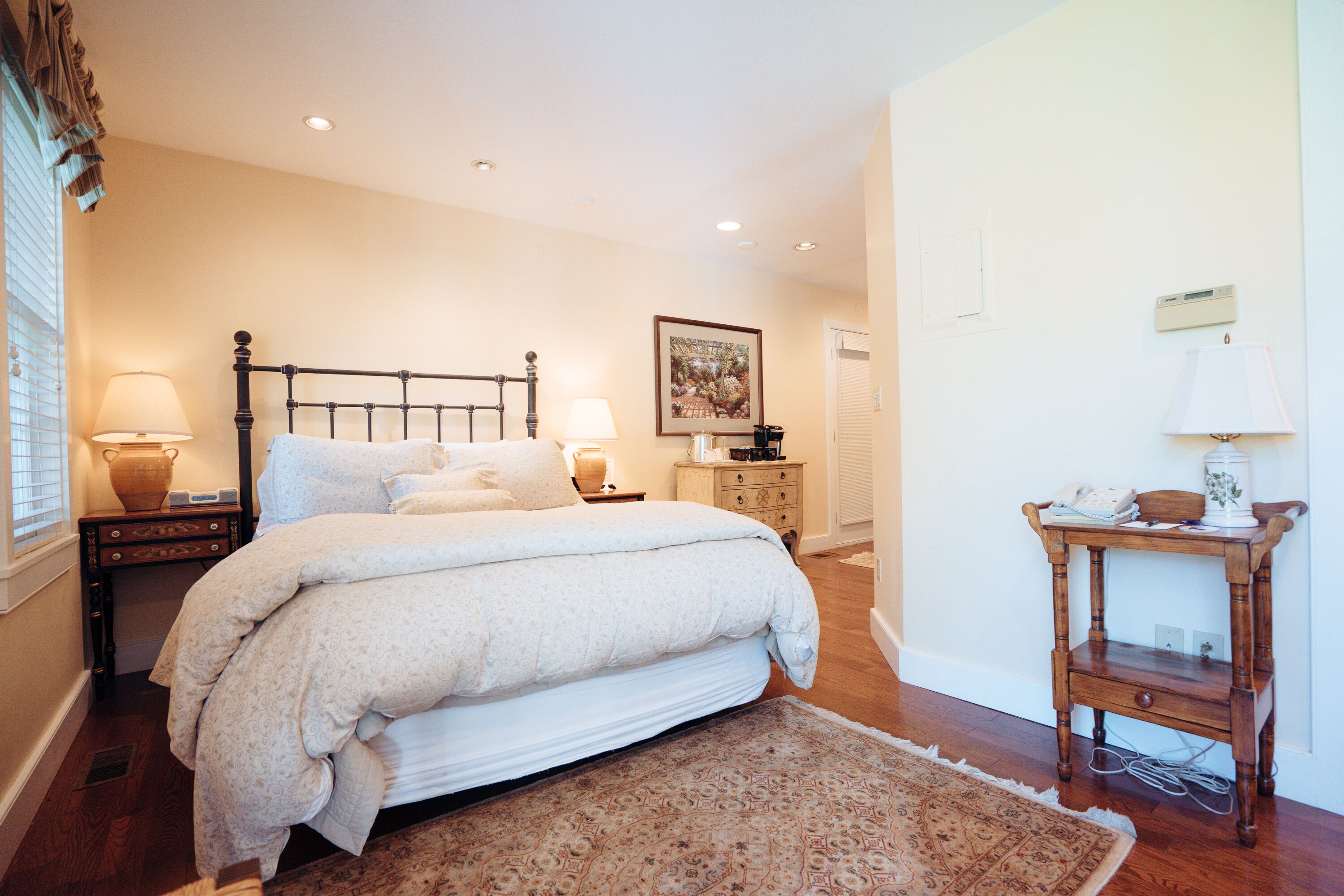 A bedroom with a large bed, bedside lamps, a wooden nightstand, and a small table with a lamp.