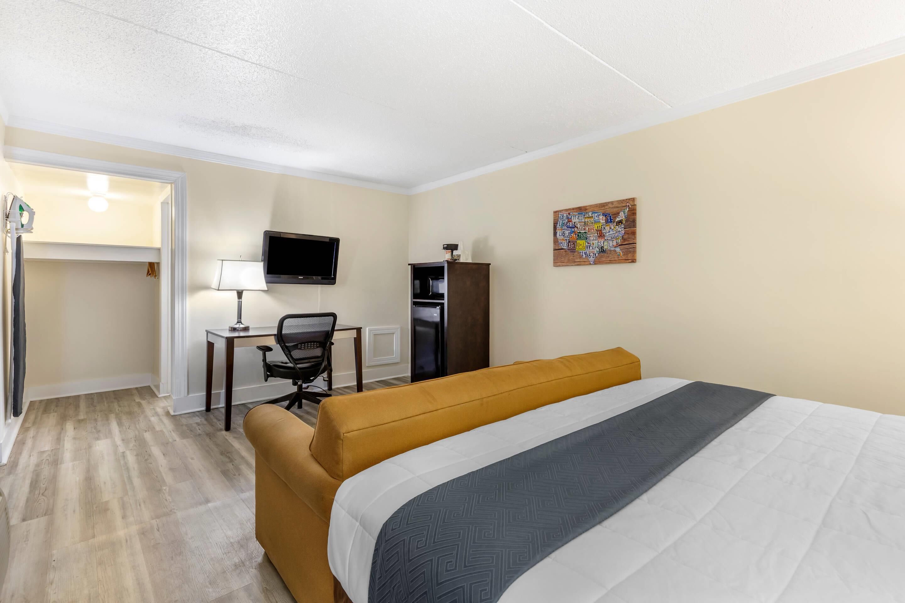 Een hotelkamer met een bed, een bureau met stoel, een televisie en een kast.