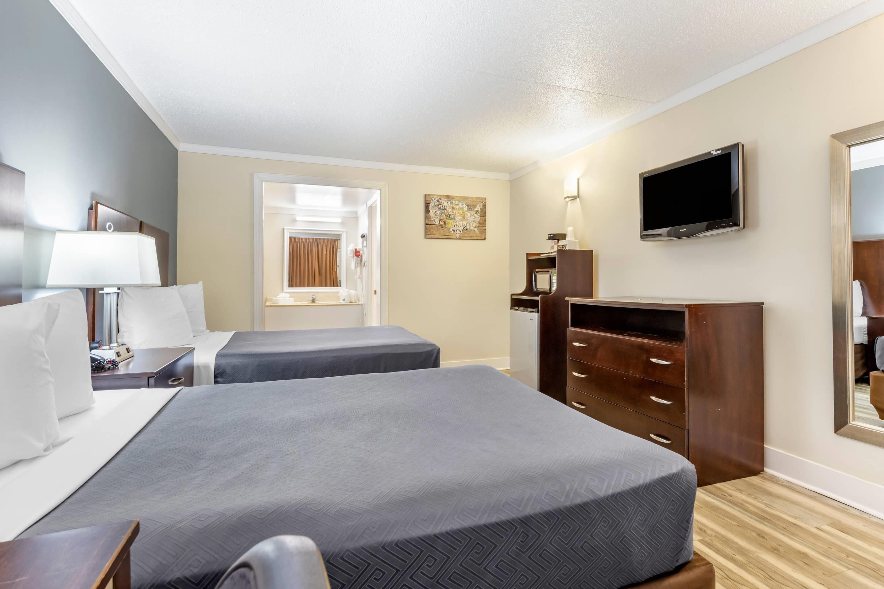 Une chambre d’hôtel avec deux lits, une télévision, une commode et un miroir.