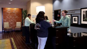 A reception area with a modern design, including a reception desk, chairs, and framed pictures on the wall. - Hampton Inn & Suites Carlsbad (Carlsbad)