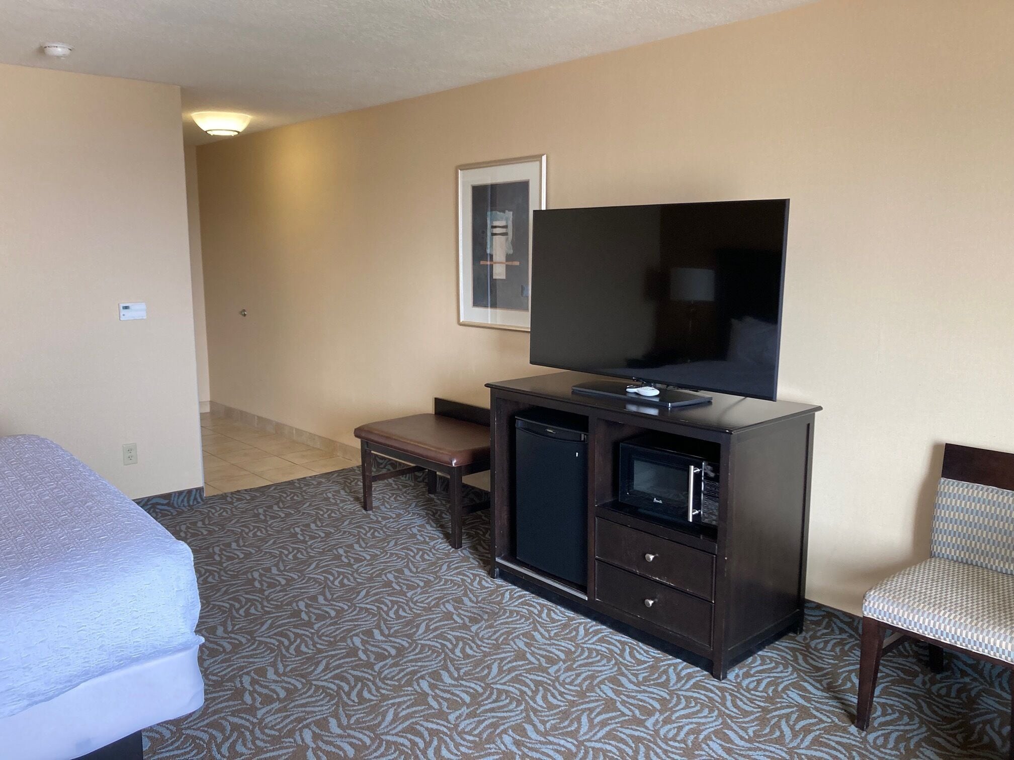 A hotel room with a bed, a desk, a television, and a microwave.