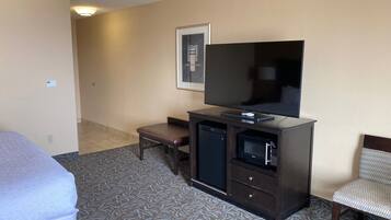 A hotel room with a bed, a desk, a television, and a microwave.