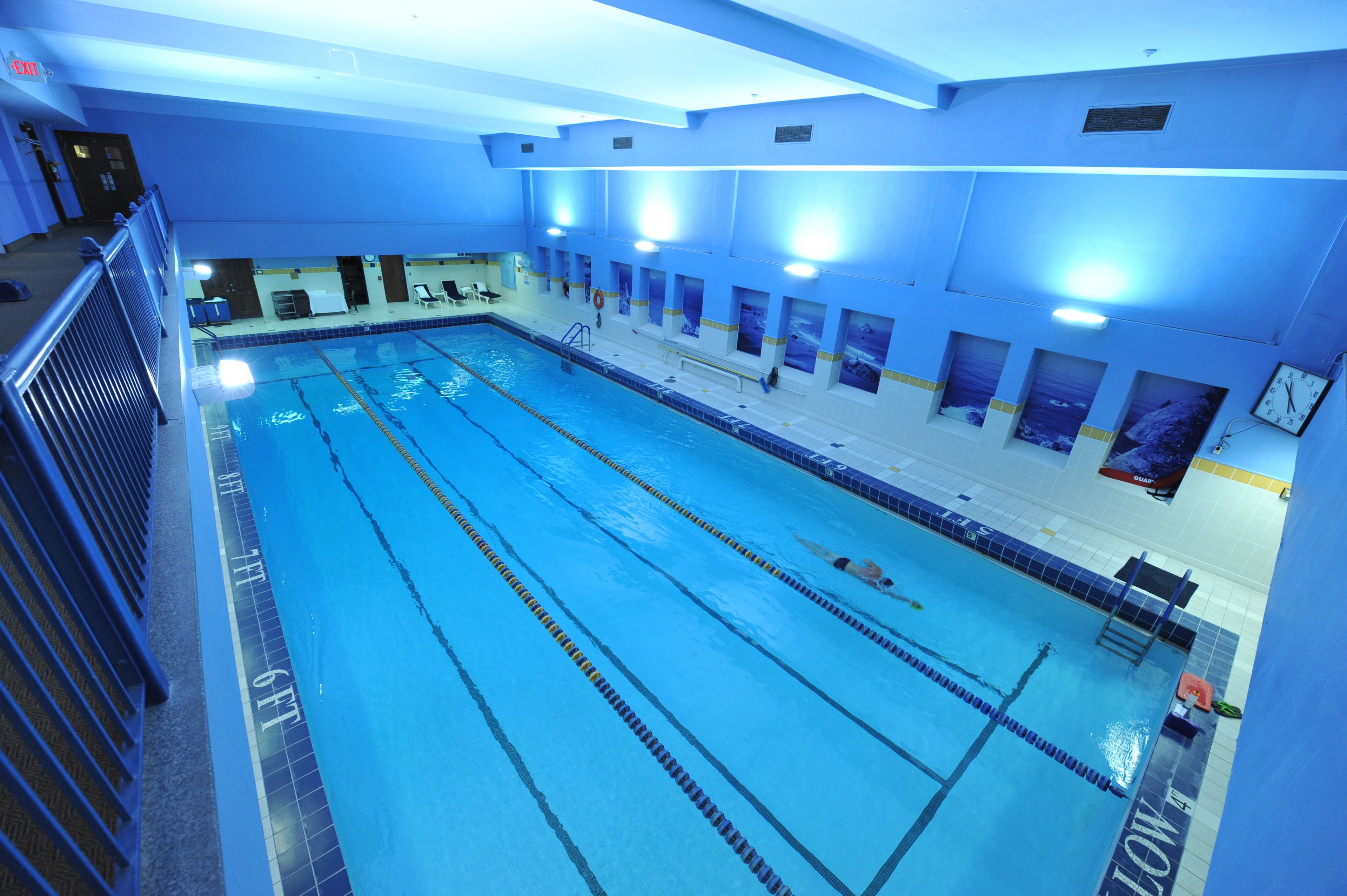 A large indoor swimming pool with multiple lanes, a lifeguard chair, and a pool ladder.