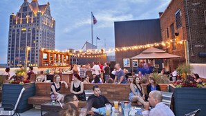 An outdoor seating area with tables and chairs, a bar, and a view of a historic building.