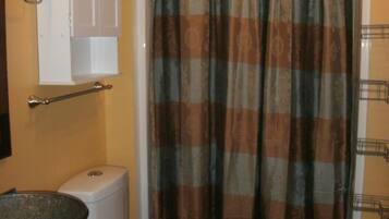 Un baño con inodoro, lavamanos, cortina de ducha y toallero.