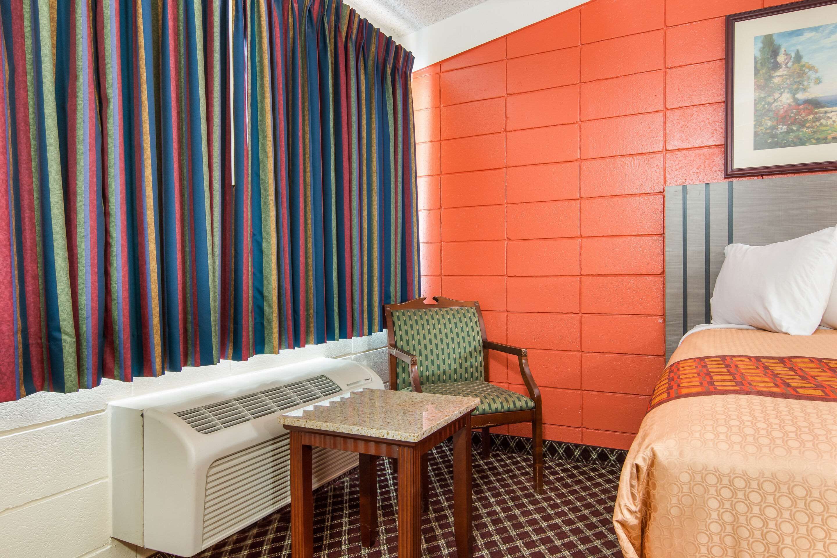 Habitació d'hotel amb un llit, una cadira, una taula i un radiador.