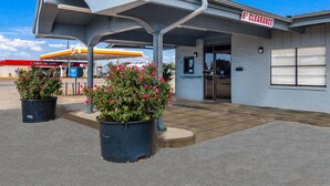 A gas station with a 6' clearance sign, outdoor seating area, and potted plants.