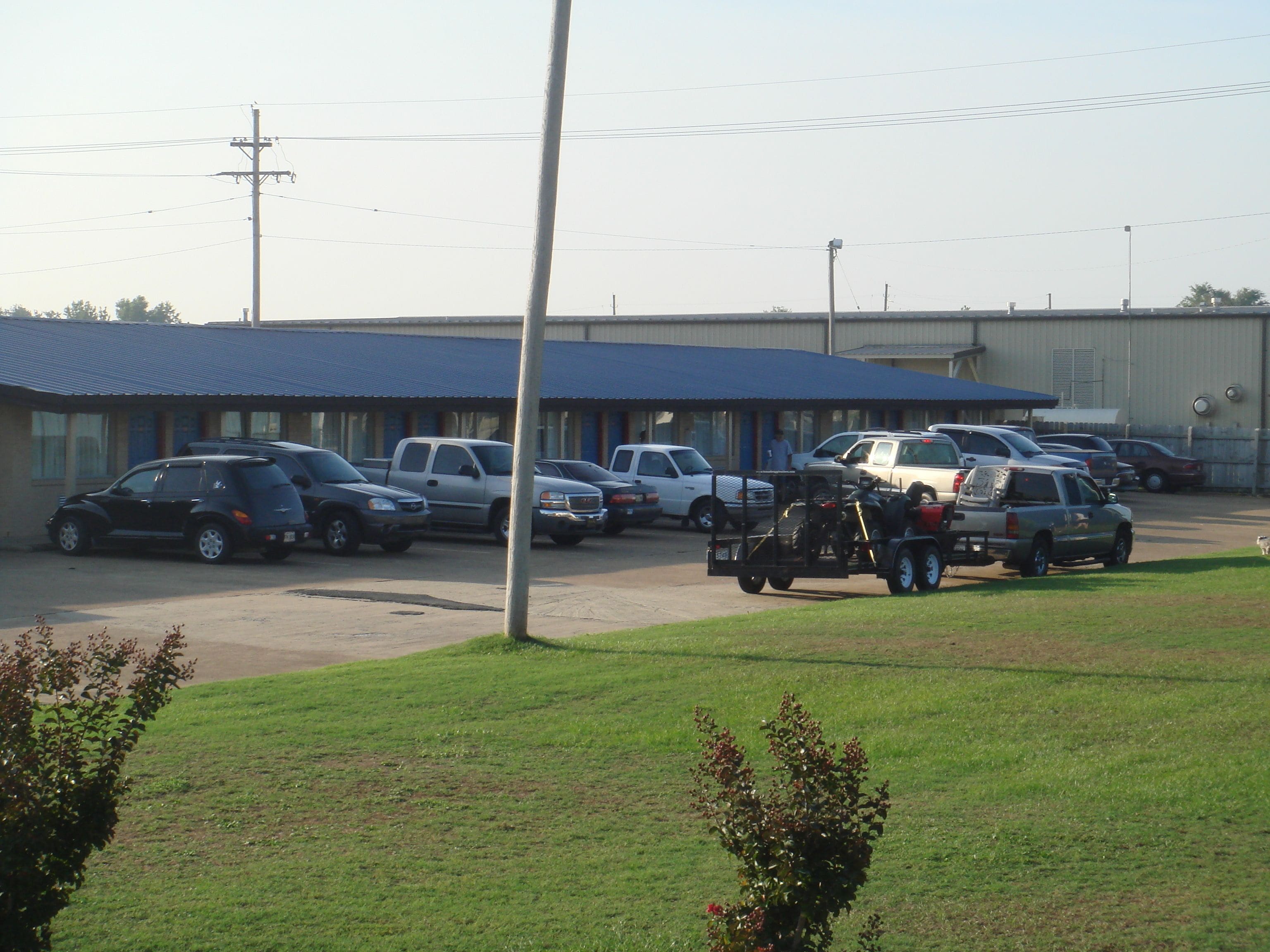 A parking lot with several cars and a motorcycle trailer.