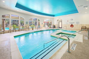 Una piscina con carriles delimitados, un puesto de socorrista y vistas al exterior.