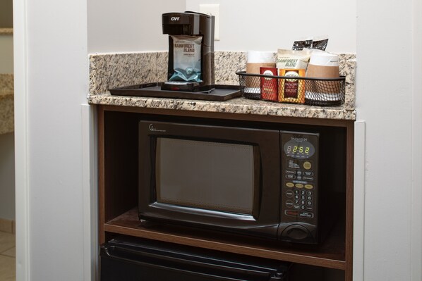 A compact kitchen with a built-in microwave and coffee maker.