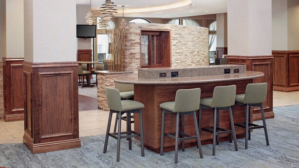 A modern bar area with a stone accent wall, a flat-screen TV, and a unique pendant light.